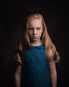 Classic studio portrait of redheaded girl in blue dress