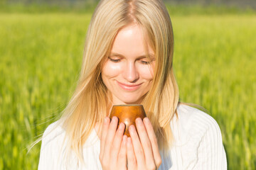 Beautiful happy woman drinking delicious healthy alternative herbal medicine tea drink in wooden...