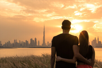 Two lovers on holiday looking at the city view during a beautiful orange sunset sky background....