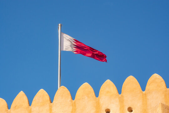 Qatar flag waving the in breeze over the merlon of Al Zubarah Fort