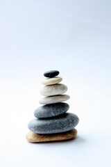 The concept of Zen. Rounded stones in the form of a pyramid on a light background. Vertical photo. There is a place for text.