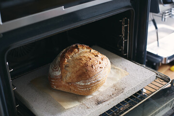 Loaf of sourdough bread out of the oven on a baking stone