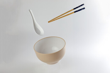 Empty oriental Japanese Chinese soup bowl spoon chopstick elevated flying in air off white