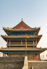 Obraz premium Xian, China - May 1, 2010: Huancheng City Wall brown stone ramparts. Corner tower is highly decorated in blues and reds. Light blue sky. Stairway up and flag.