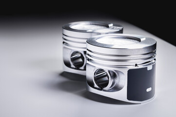 Two new piston of the internal combustion engine with dust on the sides on a gray gradient background. The concept of new engine parts