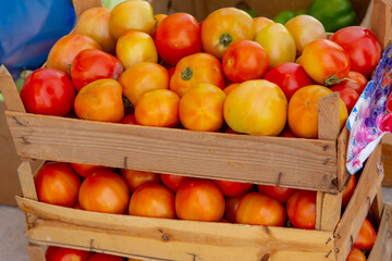 Small crates of ripe tomatoes stacked up at a market ready to be taken home