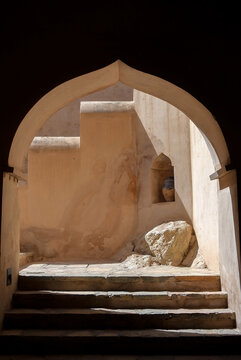 Ogee archway into an ancient fortress built into the side of a mountain with old steps heading into it