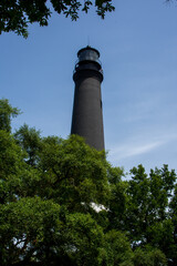 Only the top half of the Tower of the Pensacola Light appearing over green trees