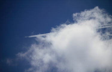 Paisaje de cielo azul con avión pasando entre grandes nubes blancas