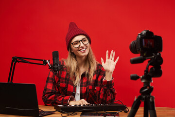 Young woman sitting at the table she working as a radio dj she smiling and waving to the camera at...