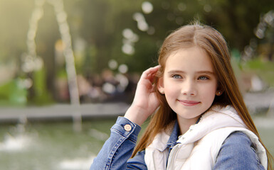 Portrait of adorable smiling little girl child preteen in the park
