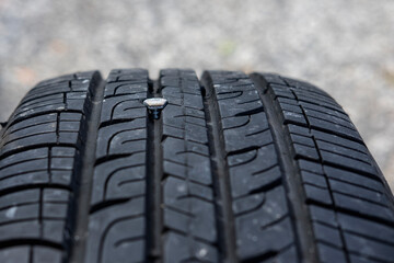 Close up macro view of car tire punctured by a metal screw that got stuck in it. Selective focus.