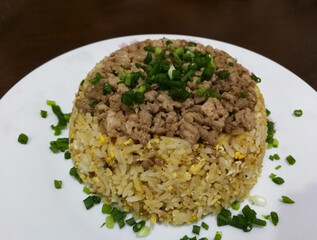 Egg fried rice topping with minced pork, seasoned and topped with spring onions On a white ceramic plate