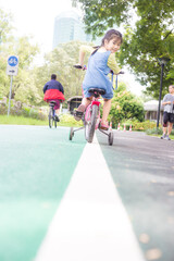 Portrait of little asian girl on a bicycle in summer city park outdoors