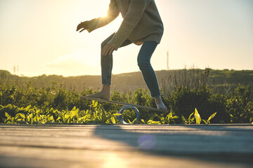 side view of healthy beautiful active woman keeping balance on the wooden balance board against the sky background at sunset summer day. Activity and outdoor concept.