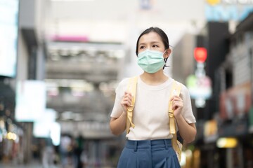 Asian girl in yellow dress with yellow bag wear surgical mask to protect the Covid-19 virus in public areas, New normal lifestyle