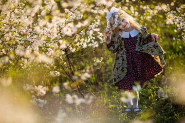 Little girl walks in a flowered garden