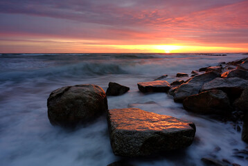 Morze Bałtyckie,wschód słońca nad kamienistym wybrzeżem,Kołobrzeg,Polska. - obrazy, fototapety, plakaty