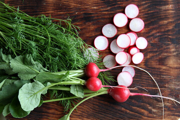 Dill and radish lie on a wooden board. Radish - red radishes, dill on wooden board View from above. Horizontal photo of fresh vegetables.