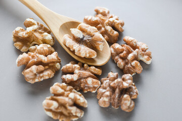 Walnuts with wooden spoon on grey background close up photo