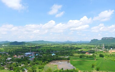 Fototapeta na wymiar Green rice field with mountains under blue sky. The fields are grassy green.It's rainy season.Sky in the rainy season