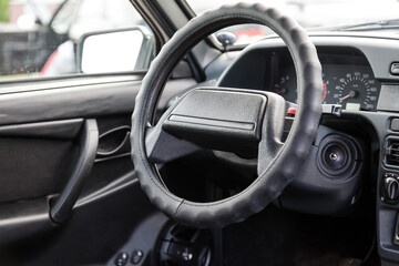 A close-up of the steering wheel of a Russian old car on a black plastic control panel with an ignition switch and sensors for engine speed and temperature inside the passenger compartment.