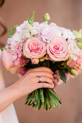 Obraz na płótnie Canvas Wedding bouquet of roses at the bride's hands