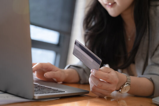 Online Shopping. Asian woman typing credit card information by laptop for shopping online.