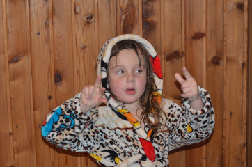 Caucasian child in the bathroom in a bathrobe on a wooden background