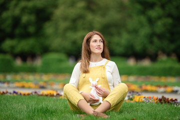 Fototapeta premium Expecting young female mother posing in park holding plush toy