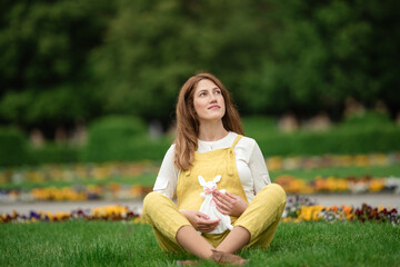 Fototapeta na wymiar Expecting young female mother posing in park holding plush toy