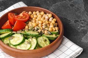 Clay plate of chickpeas and cut cucumbers and tomatoes. Healthy eating