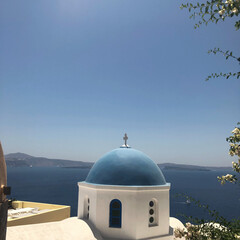 Fototapeta na wymiar Greek orthodox church with sailboat in Santorini, Greece