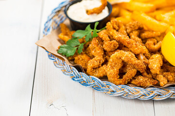 Crispy Breaded Clam Strips Snack Size. Deep Fried Breaded Clams Fingers and French Fried Potatoes with Tartar Dipping Sauce on a wooden board. Selective focus.