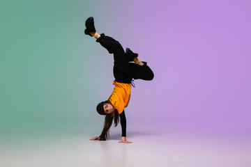 Fototapeta na wymiar Beautiful sportive girl dancing hip-hop in stylish clothes on colorful gradient background at dance hall in neon light. Youth culture, movement, style and fashion, action. Fashionable bright portrait.