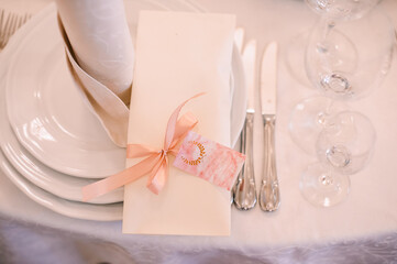 Banquet, restaurant. Table setting with tablecloth. White plates, cutlery, glasses, napkin, floral arrangements, food, chairs, flowers