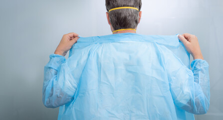 Doctor wearing blue single use gown for covid19 medical procedure for coronavirus protection