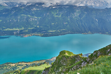 Landscape with Swiss Alps mountains, green nature and Lake Brienz (Brienzersee). Photo taken at Hardergrat ridge trail / hike, near Interlaken, Switzerland. 