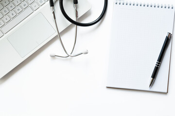 Workplace of doctor with laptop and stethoscope on keyboard and notepad with pen isolated. Close up. Concept medical, business. Backround