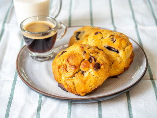 Chunky chewy chocolate chip soft cookies with cups of coffee and milk for breakfast, selective focus on cookies