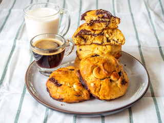 Chunky chewy chocolate chip soft cookies with cups of coffee and milk for breakfast, selective focus on cookies