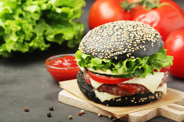 A black burger with vegetables and beef meat