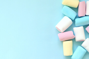 Colorful soft pastel marshmallows on a blue background. Selective focus. Space for text. Festive background. Copy space