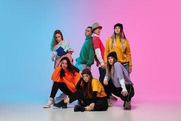 Group of dancers, boys and girls dancing hip-hop in stylish clothes on colorful gradient background at dance hall in neon. Youth culture, movement, style and fashion, action. Fashionable portrait.