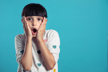 portrait of a cute surprised girl on a blue background