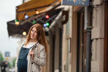 Beautiful young pregnant woman wearing casual clothes walking through the city streets. concept of motherhood and pregnancy. street portrait among cars close up view.