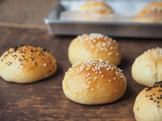 Soft bread bun with black and white sesame seed topping on wooden background