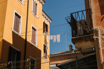 Fototapeta na wymiar Old lady hangs freshly washed laundry to dry in the sun in Venice, Italy.