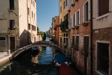 Fototapeta na wymiar Empty canal of Cannaregio district, only two people are sitting on the bridge in Venice, Italy.