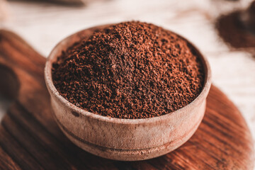 Bowl with coffee powder on wooden table, closeup